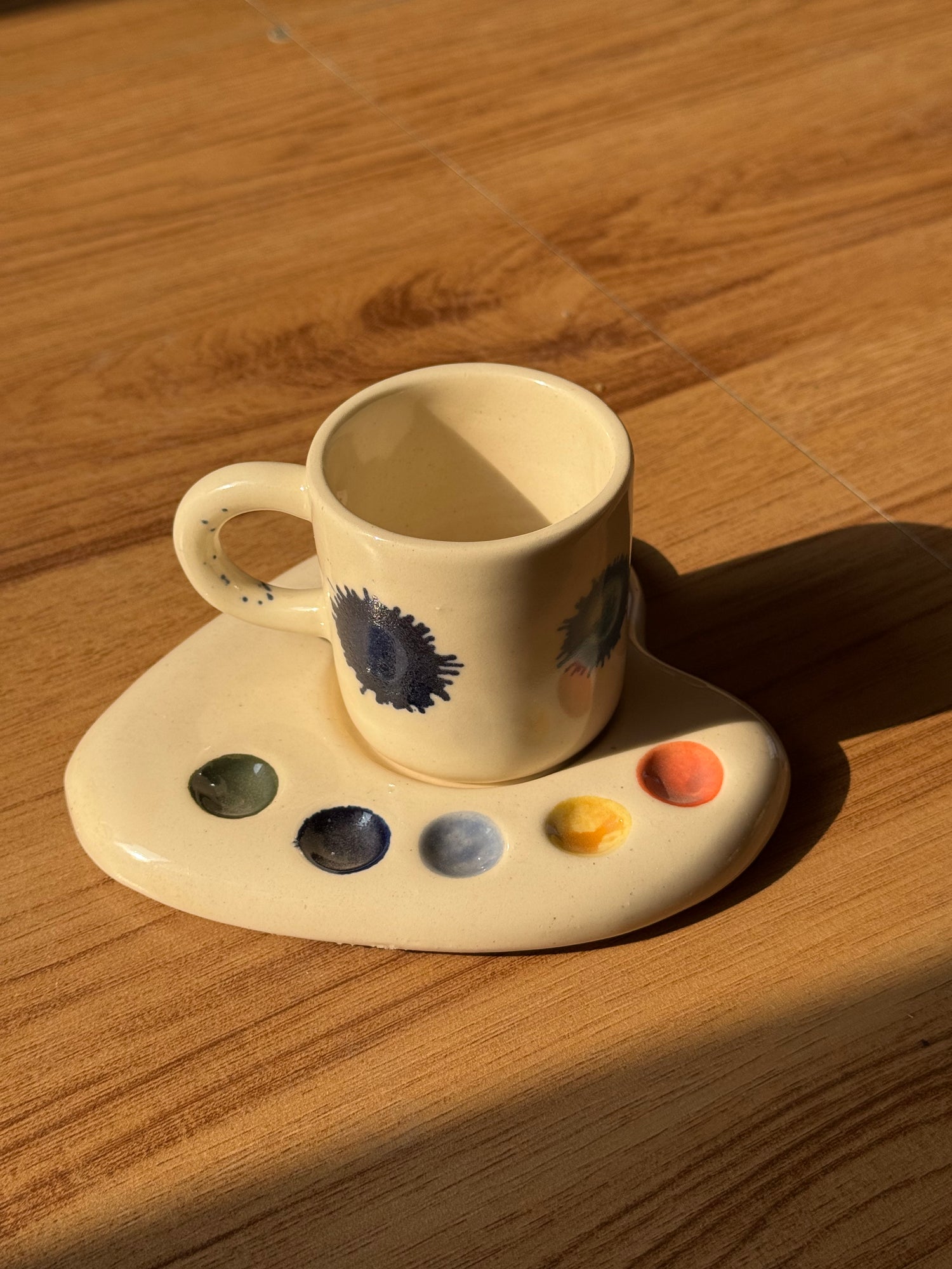 Artist Palette espresso cup with blue paint details on a palette saucer on a wooden table
