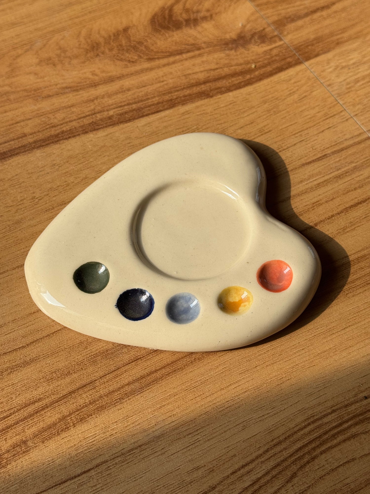Cream artist palette saucer with green, navy, blue, yellow and coral paint dots