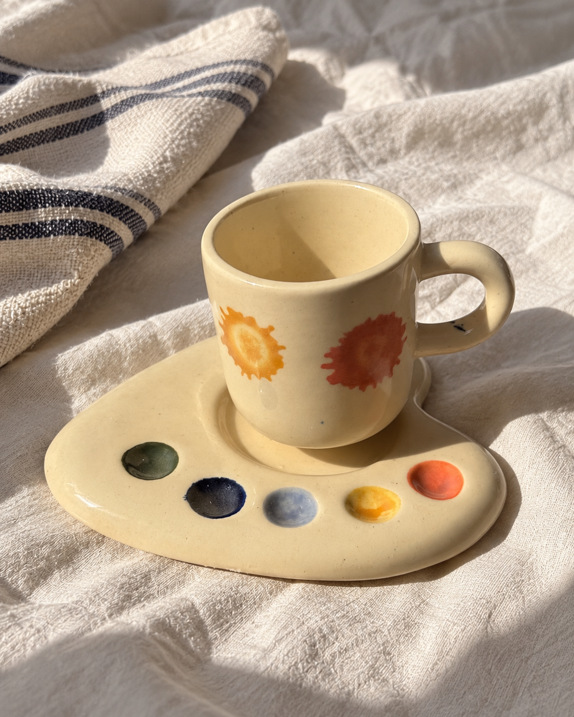 Artist Palette espresso set on white linen beside a blue-striped cloth