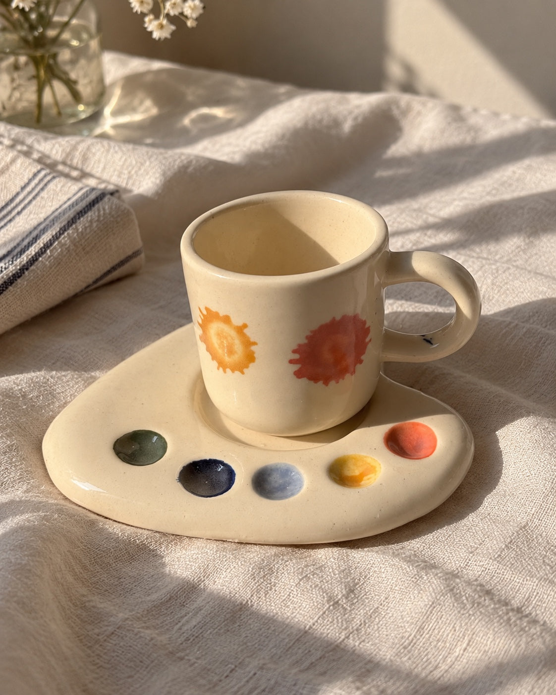 Artist Palette ceramic espresso mug and palette-shaped saucer on sunlit white linen