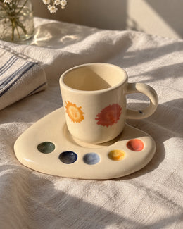 Artist Palette ceramic espresso mug and palette-shaped saucer on sunlit white linen