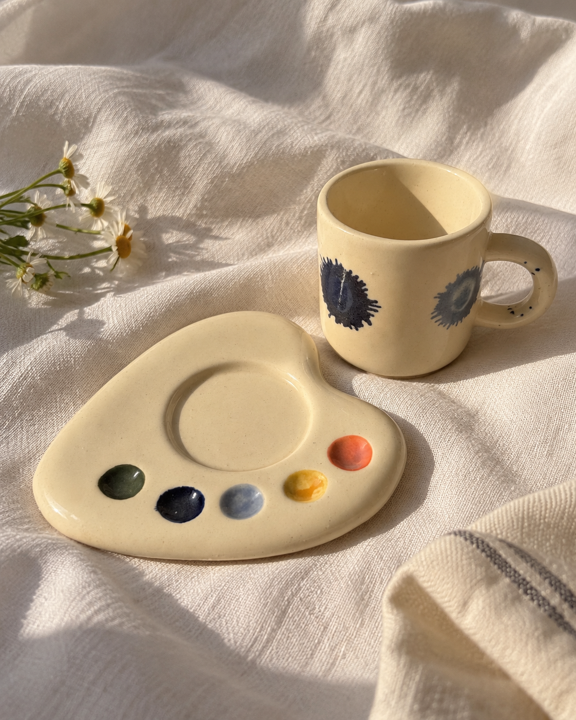 Ceramic espresso mug beside its matching palette-shaped saucer, showing the circular cup recess