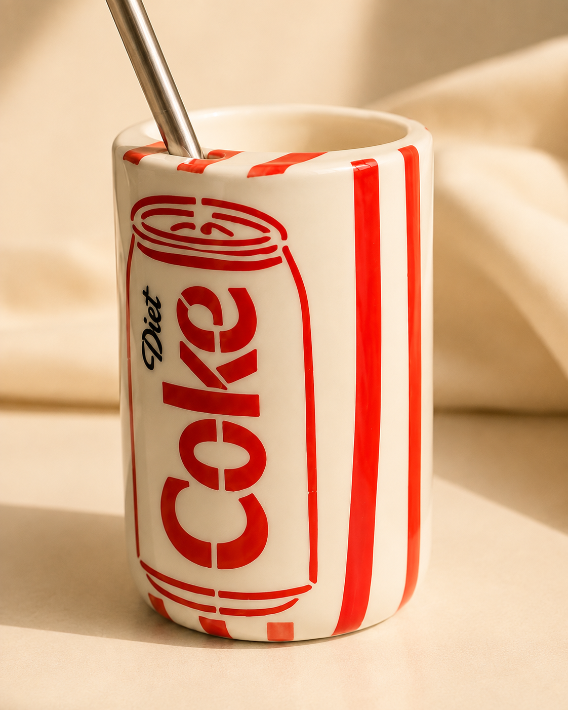 Close-up of red and off-white retro cola can ceramic mug with stainless steel straw
