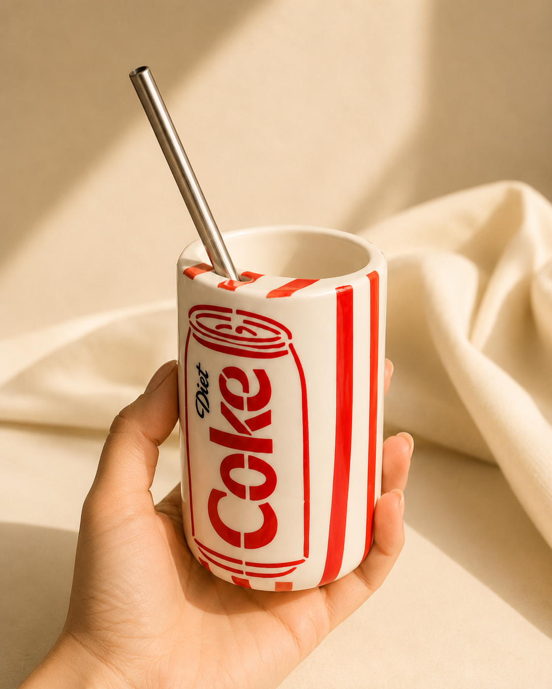 Hand holding retro cola can-inspired ceramic mug with stainless steel straw