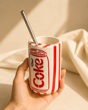Hand holding retro cola can-inspired ceramic mug with stainless steel straw