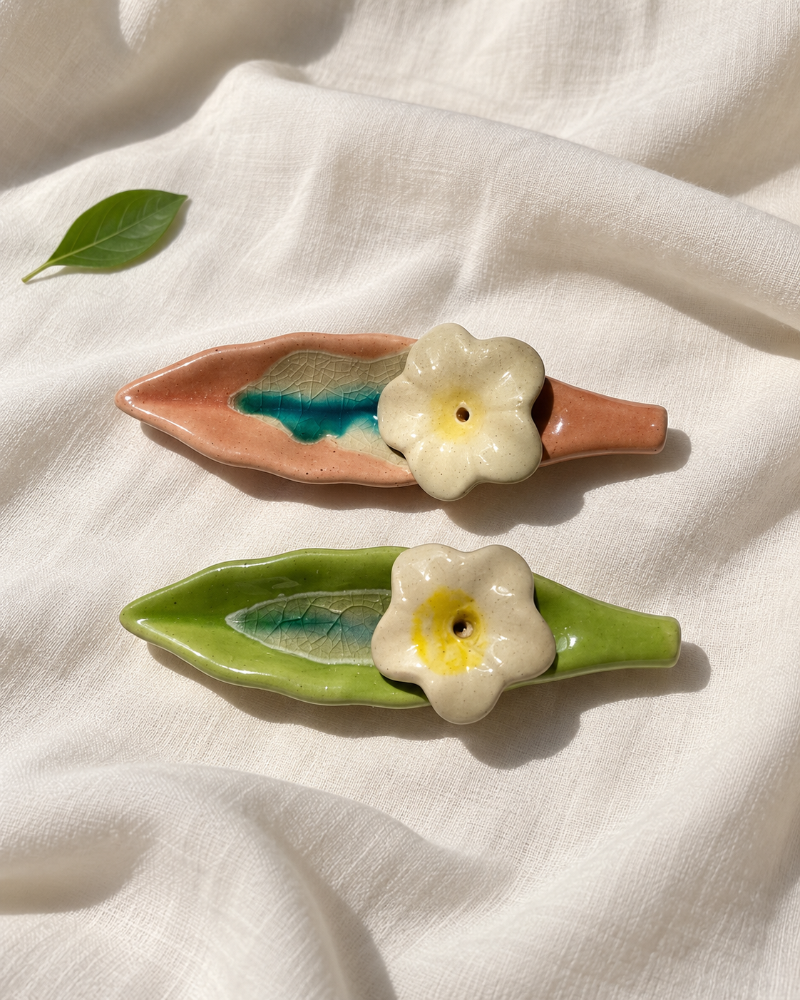 Leaf and Flower Ceramic Incense Holders - Green and Pink, Set of 2, displayed on fabric