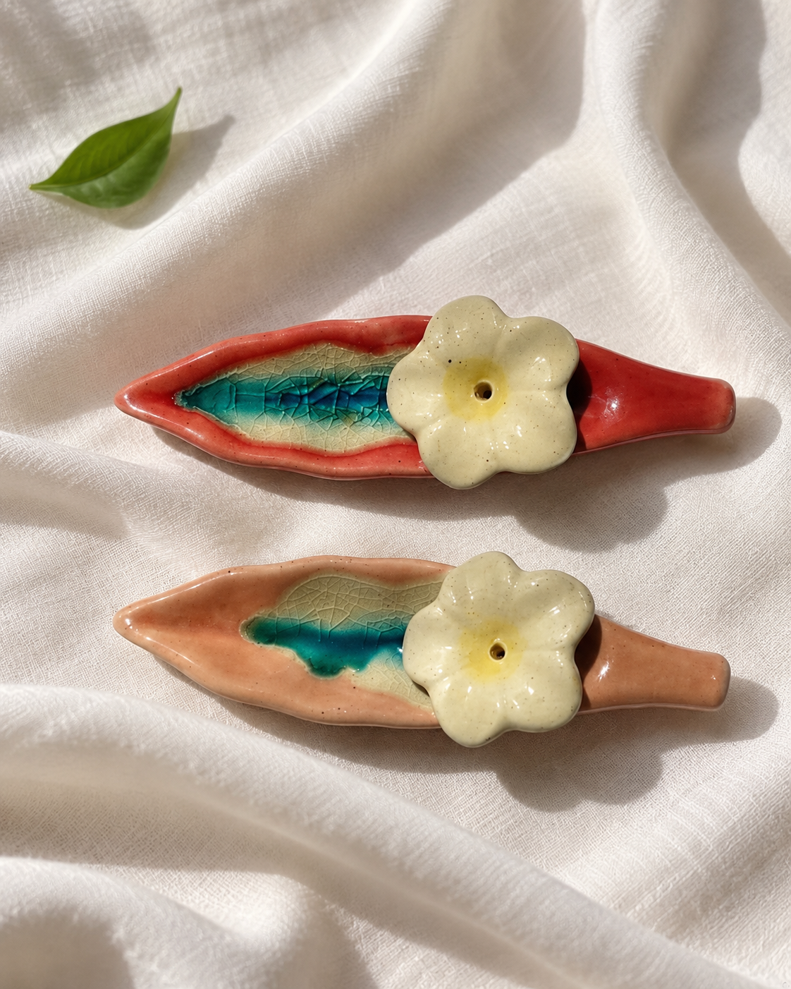 Leaf and Flower Ceramic Incense Holders - Red and Pink, Set of 2, displayed on fabric