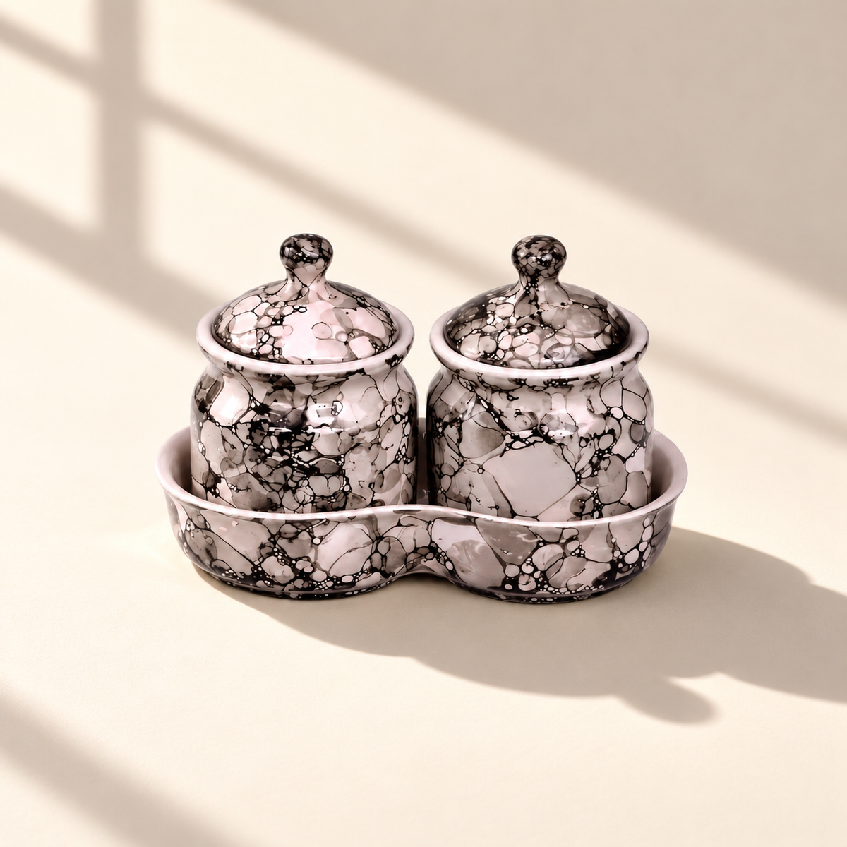 Blush-grey marble ceramic condiment jar set of two with matching lids and tray on an ivory backdrop